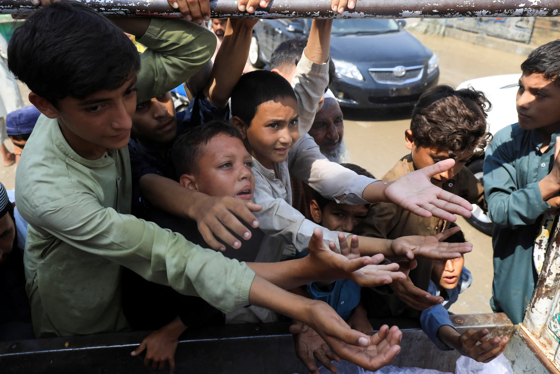 Boys, victims of the flood, reach out for food from a relief worker, following rains and floods during the monsoon season in Nowshera, Pakistan August 30, 2022. REUTERS/Fayaz Aziz