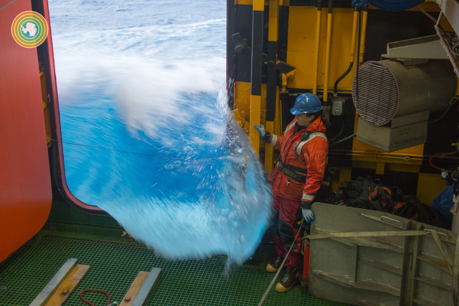 During a SOCCOM expedition on the R/V Nathaniel B. Palmer, a scientist watches as a large wave enters the Baltic Room, where the operations crew deploys and recovers equipment. She is strapped into a safety line and is waiting for a moment to safely perform the task at hand. ⁠(SOCCOM Project/ Greta Shum)