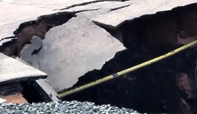 Watch pavement buckle and crumble into large sinkhole