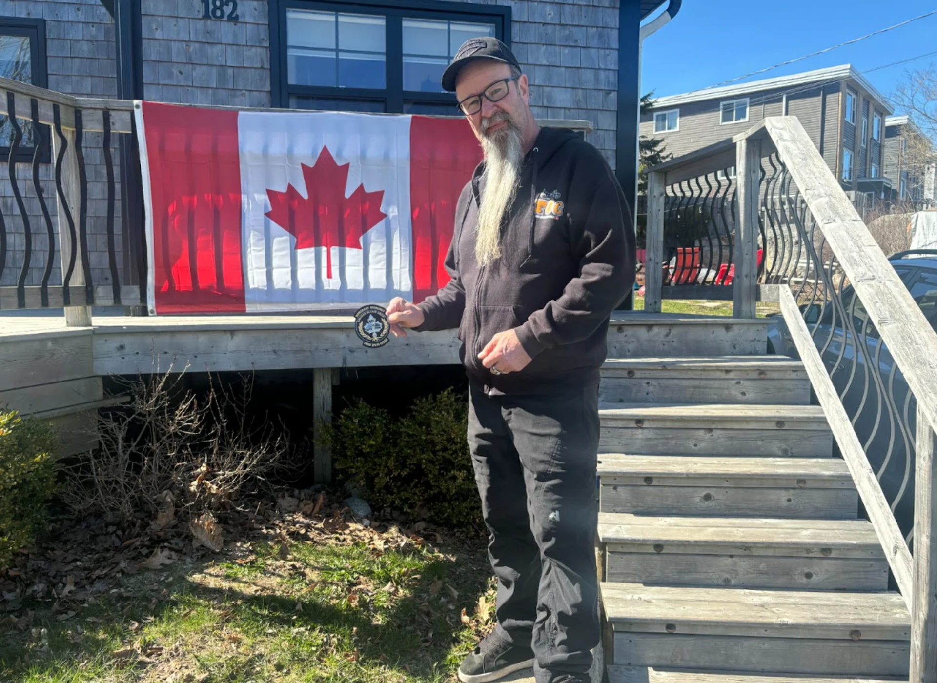 Angus Cameron in front of his Canadian flag on display in front of his home in Halifax (The Weather Network)