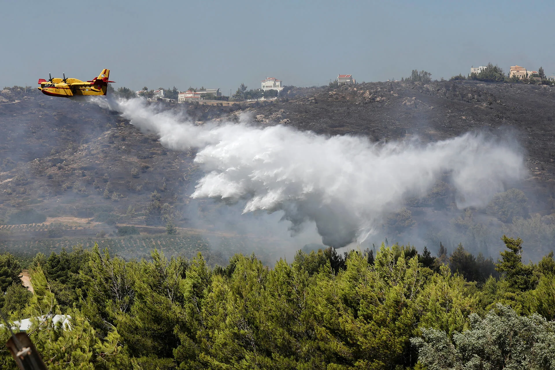 A Canadair aircraft makes a water drop as a wildfire burns in the Pikermi suburb of Athens, Greece, on July 20, 2022. (REUTERS/ Louiza Vradi)
