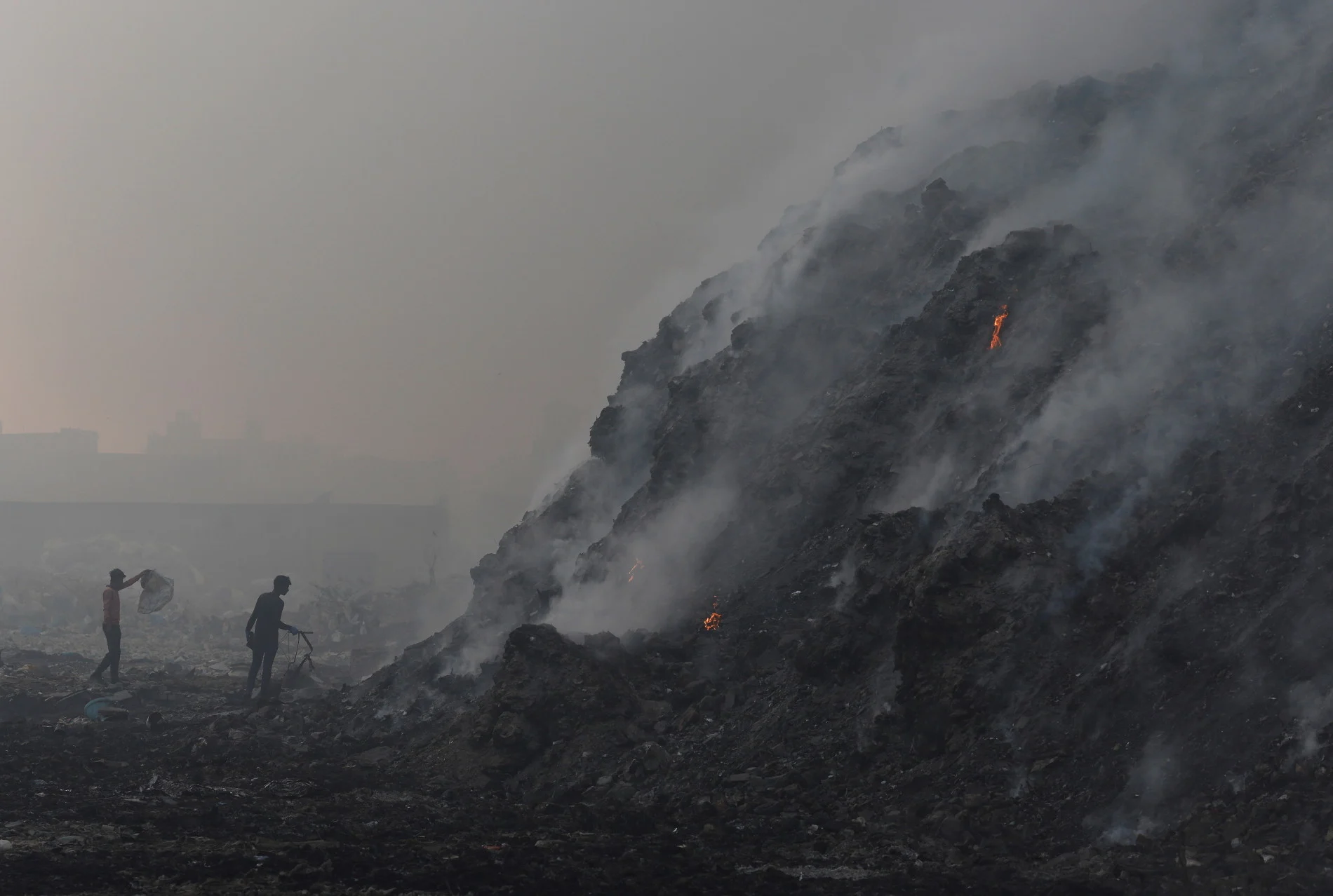  Waste collectors look for recyclable materials as smoke billows from burning garbage at the Bhalswa landfill site in New Delhi, India, April 27, 2022. (REUTERS/Adnan Abidi)