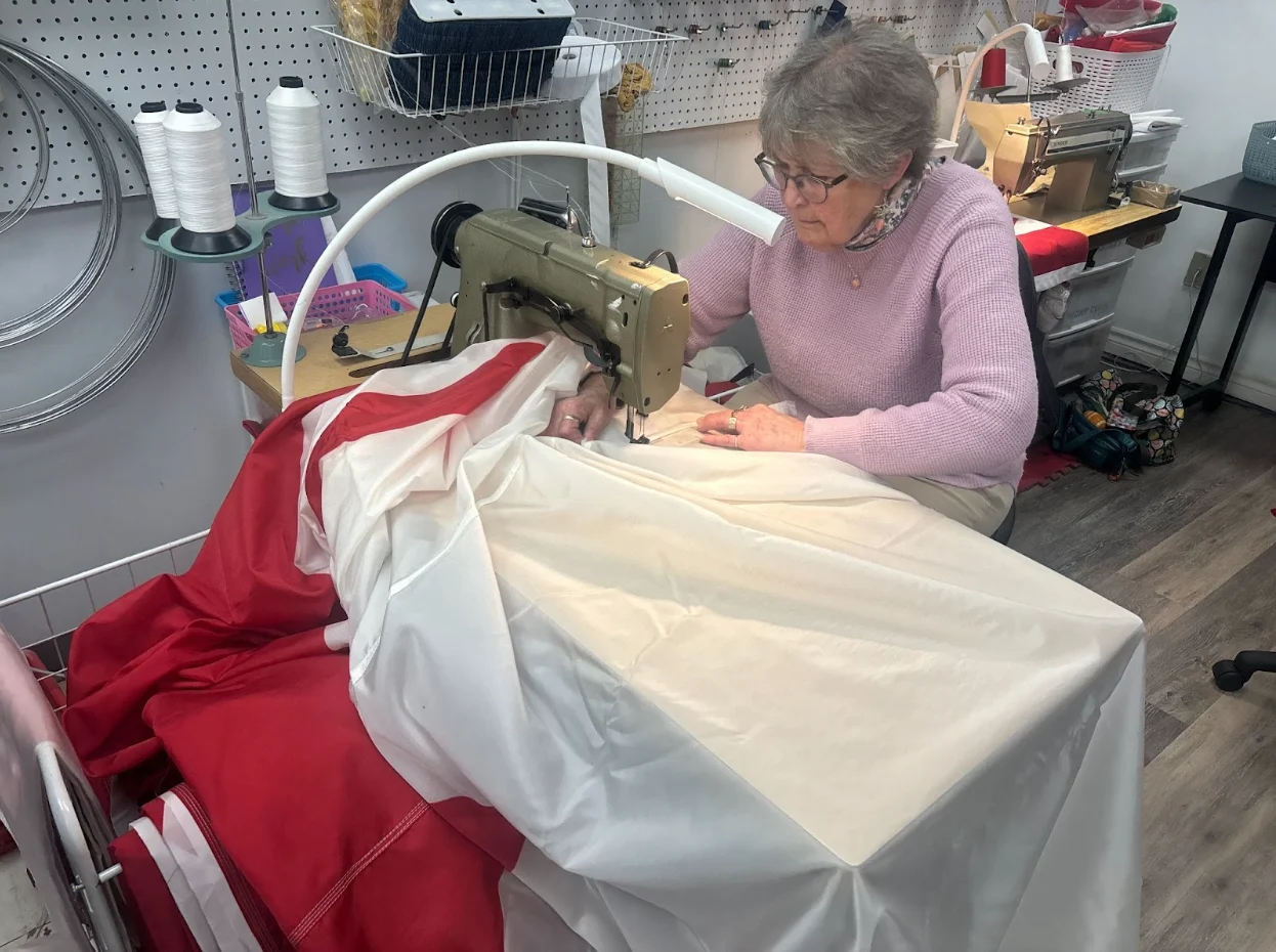 Nathan Coleman - Flag Series Part 2: Photo by Nathan Coleman showing a worker sewing together a flag at the Flag shop in Dartmouth, NS