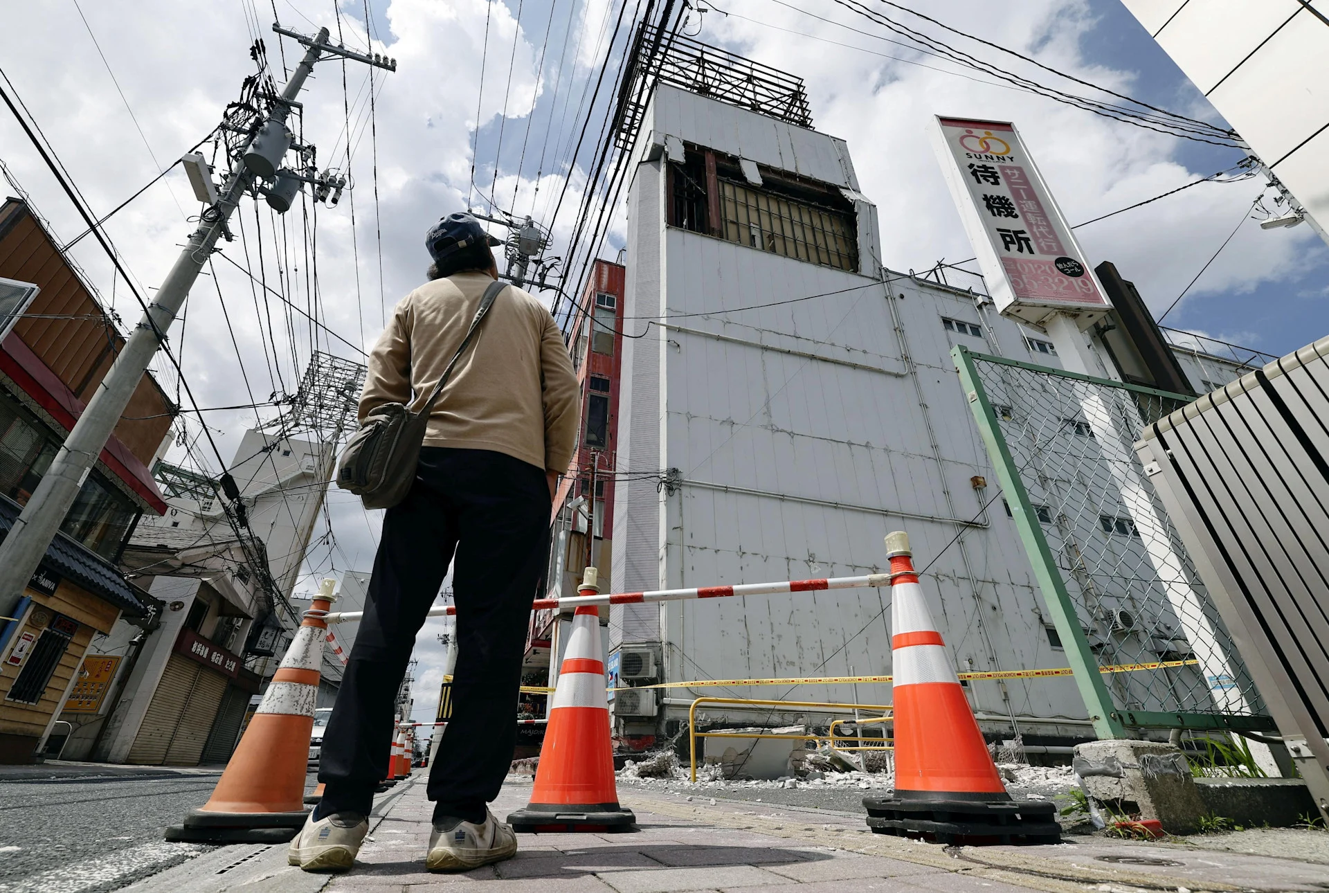 REUTERS: A man looks at a building with a wall damaged in the earthquake in Hachinohe, Aomori Prefecture, Japan, June 25, 2026, in this photo taken by Kyodo. Kyodo/via REUTERS