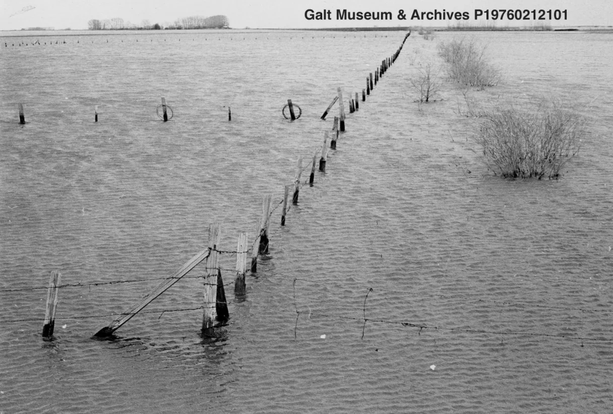 Farmland and roads are flooded following the April/May snowstorms. The top of a barbed wire fence and bushes are visible. 1967. Courtesy Lethbridge Historical Society (Facebook)