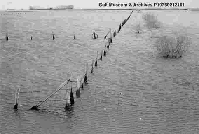 Farmland and roads are flooded following the April/May snowstorms. The top of a barbed wire fence and bushes are visible. 1967. Courtesy Lethbridge Historical Society (Facebook)