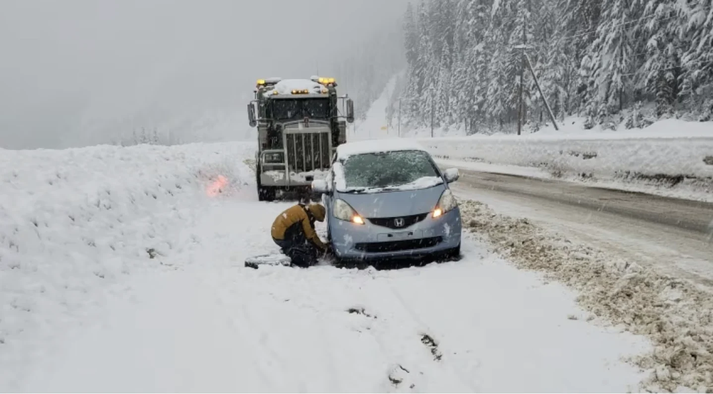 CBC: A driver changes a tire during a snow storm on the Coquihalla Highway on Wednesday. (Al Quiring)