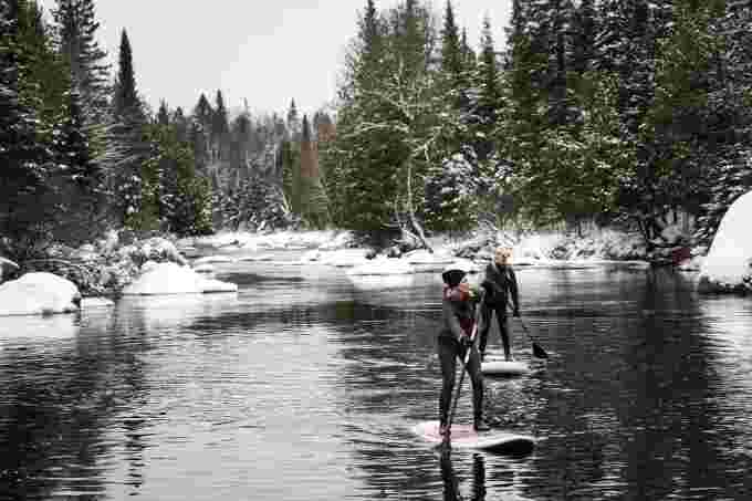 Deux femmes se baladent avec leur planche à pagaie sur une rivière