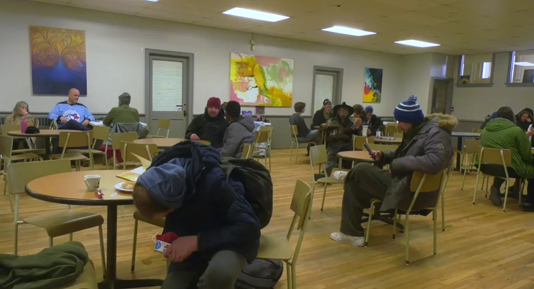 People seated around small tables throughout a room taking shelter from the cold. (Mark Robinson)