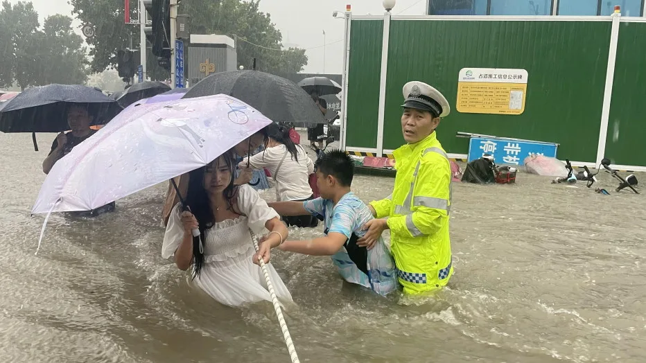REUTERS: A traffic police officer guides residents to cross a flooded road with a rope during heavy rainfall in Zhengzhou, Henan province, China July 20, 2021. Picture taken July 20, 2021. China Daily via REUTERS
