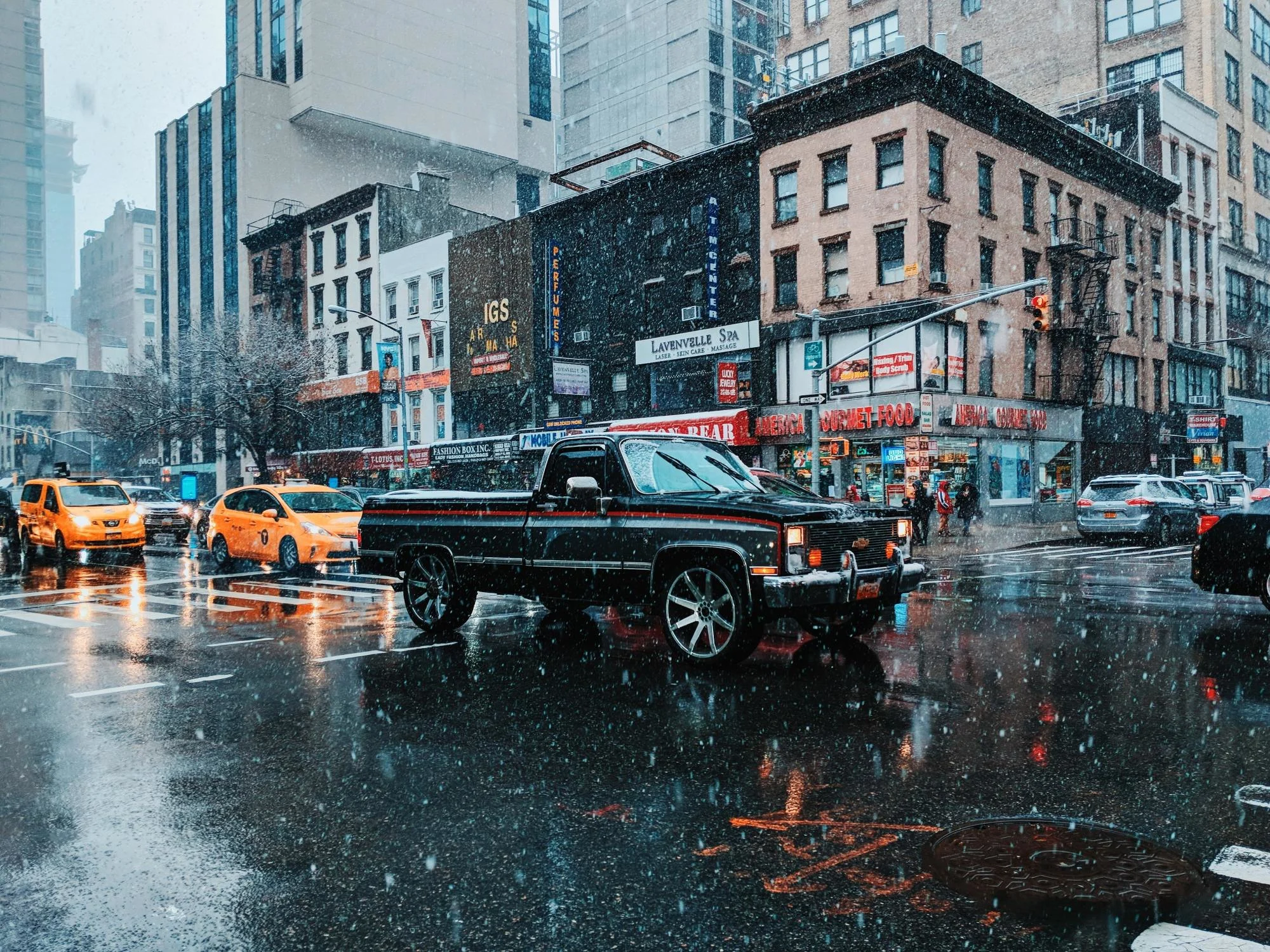 (UNSPLASH/Patrick Tomasso) Snow falling New York City street car traffic