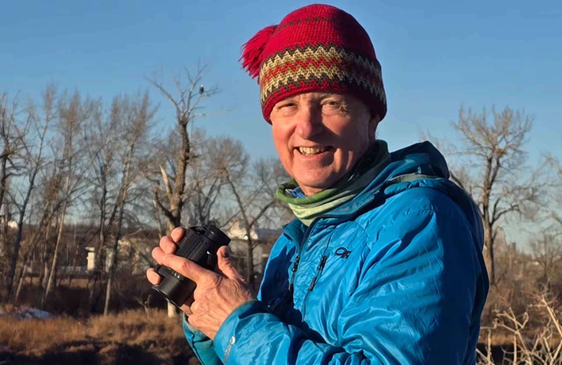 CBC: Calgary naturalist Brian Keating pictured in Calgary's Carburn Park, with a bald eagle visible in a tree behind him. (Amir Said/CBC)