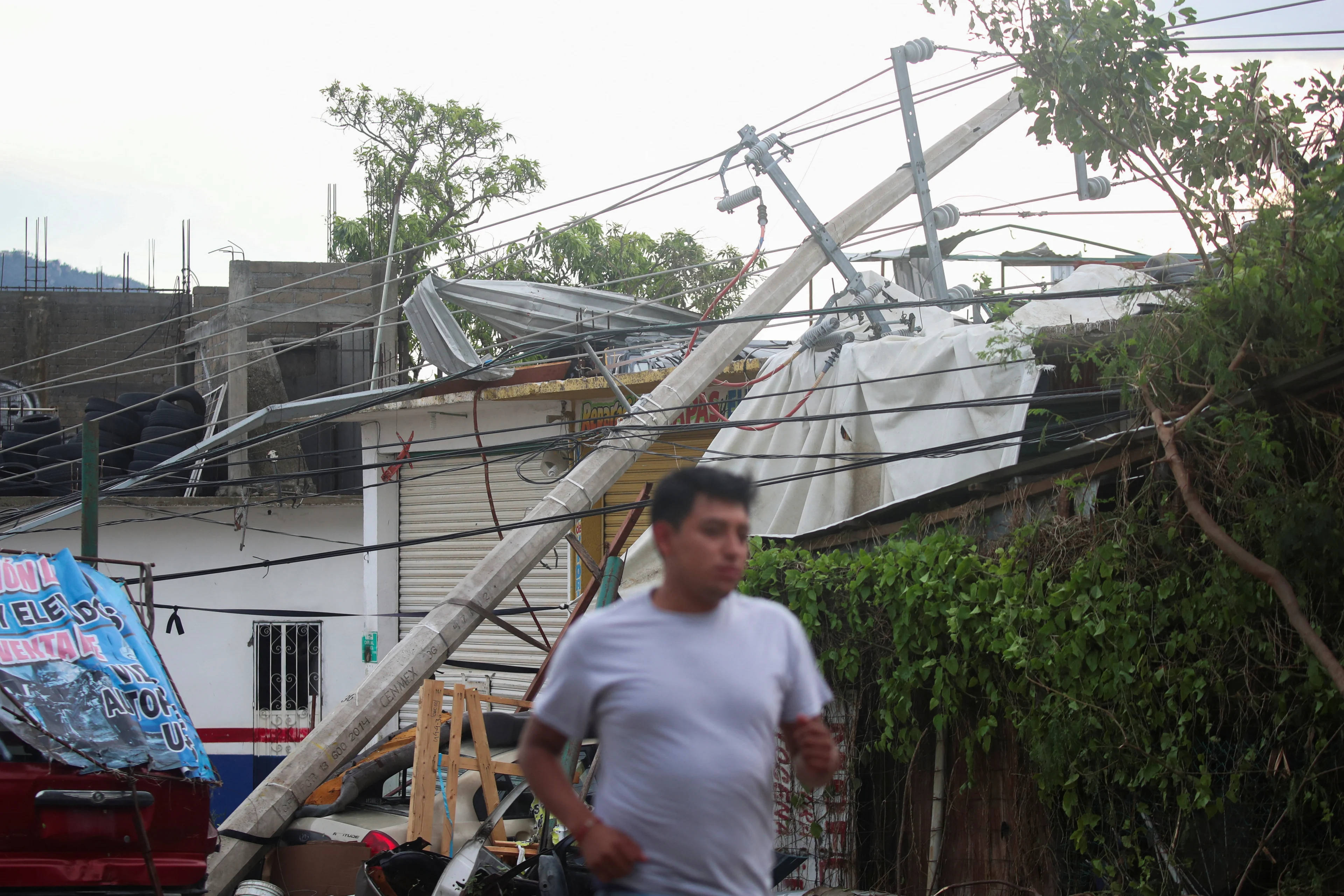 Reuters: Um homem passa correndo por um poste de eletricidade caído perto da entrada de Acapulco após a passagem do furacão Otis, no estado mexicano de Guerrero, México, 25 de outubro de 2023. REUTERS/Henry Romero