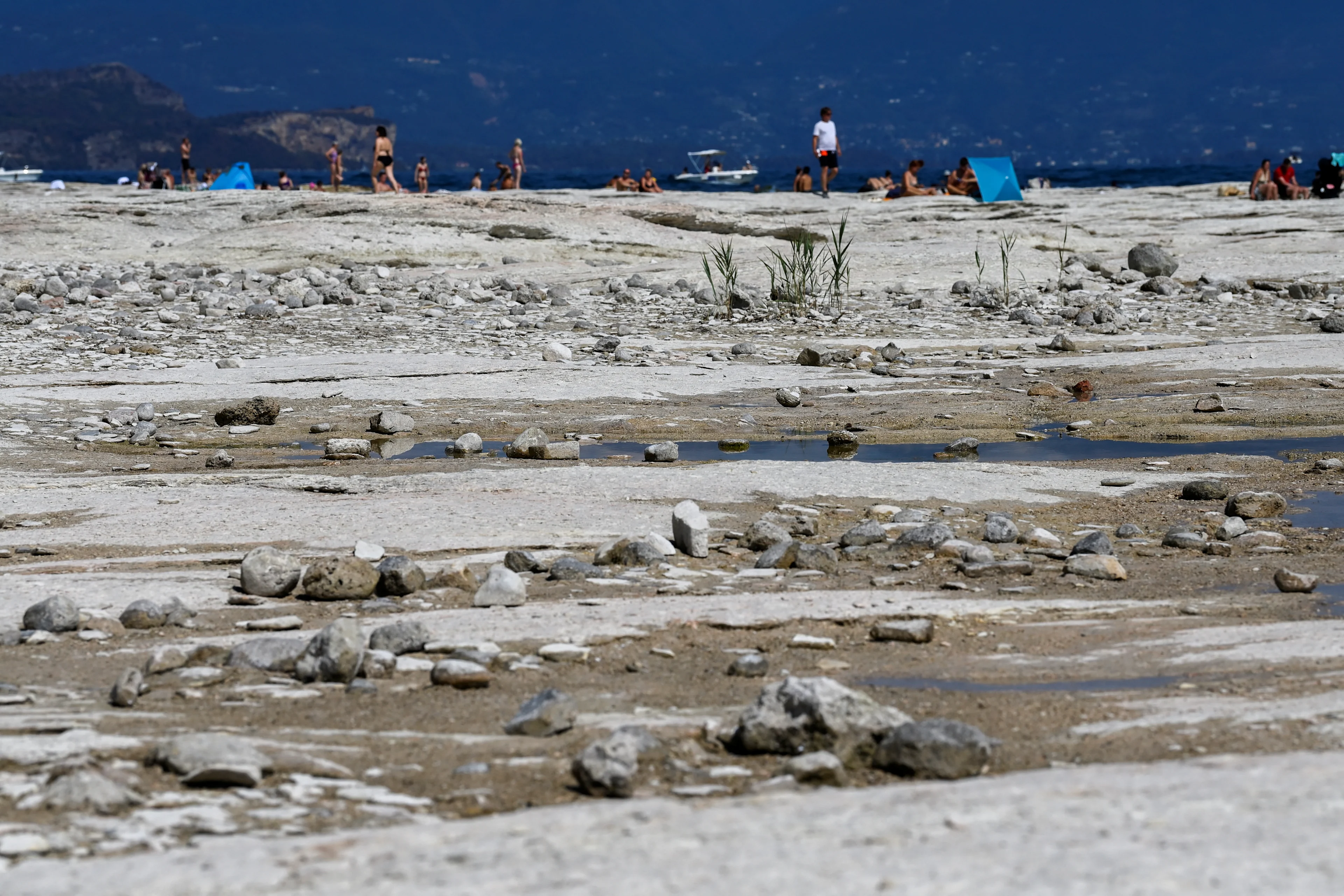 reuters: FILE PHOTO: Underwater rocks emerge from the water of Lake Garda after northern Italy experienced the worst drought in 70 years in Sirmione, Italy, August 16, 2022. REUTERS/Flavio Lo Scalzo