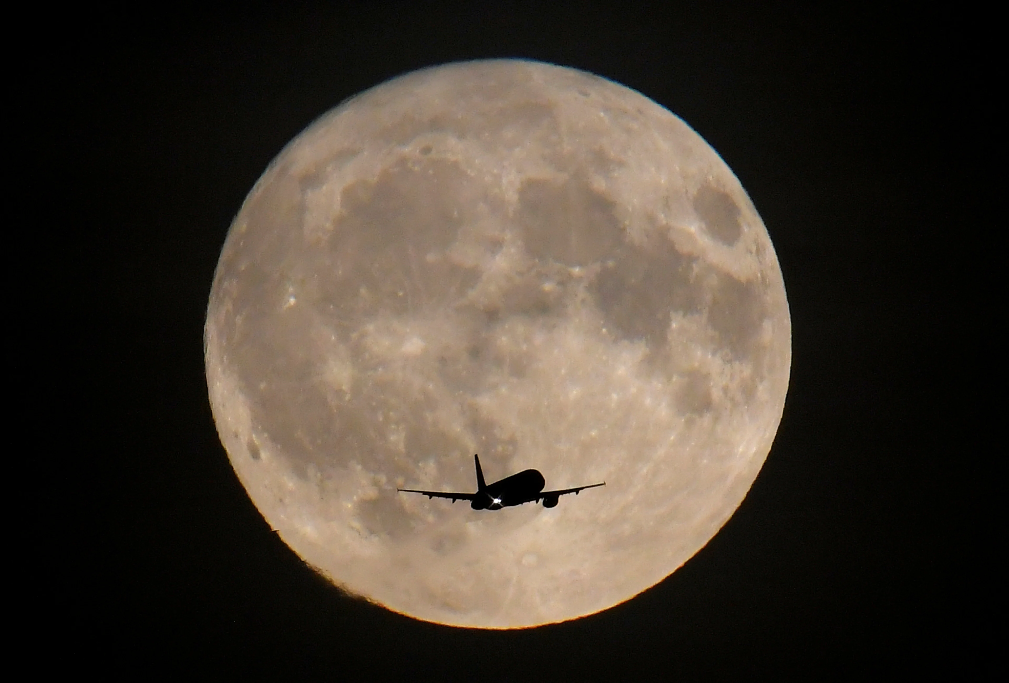 Plane in front of moon REUTERS Toby Melville