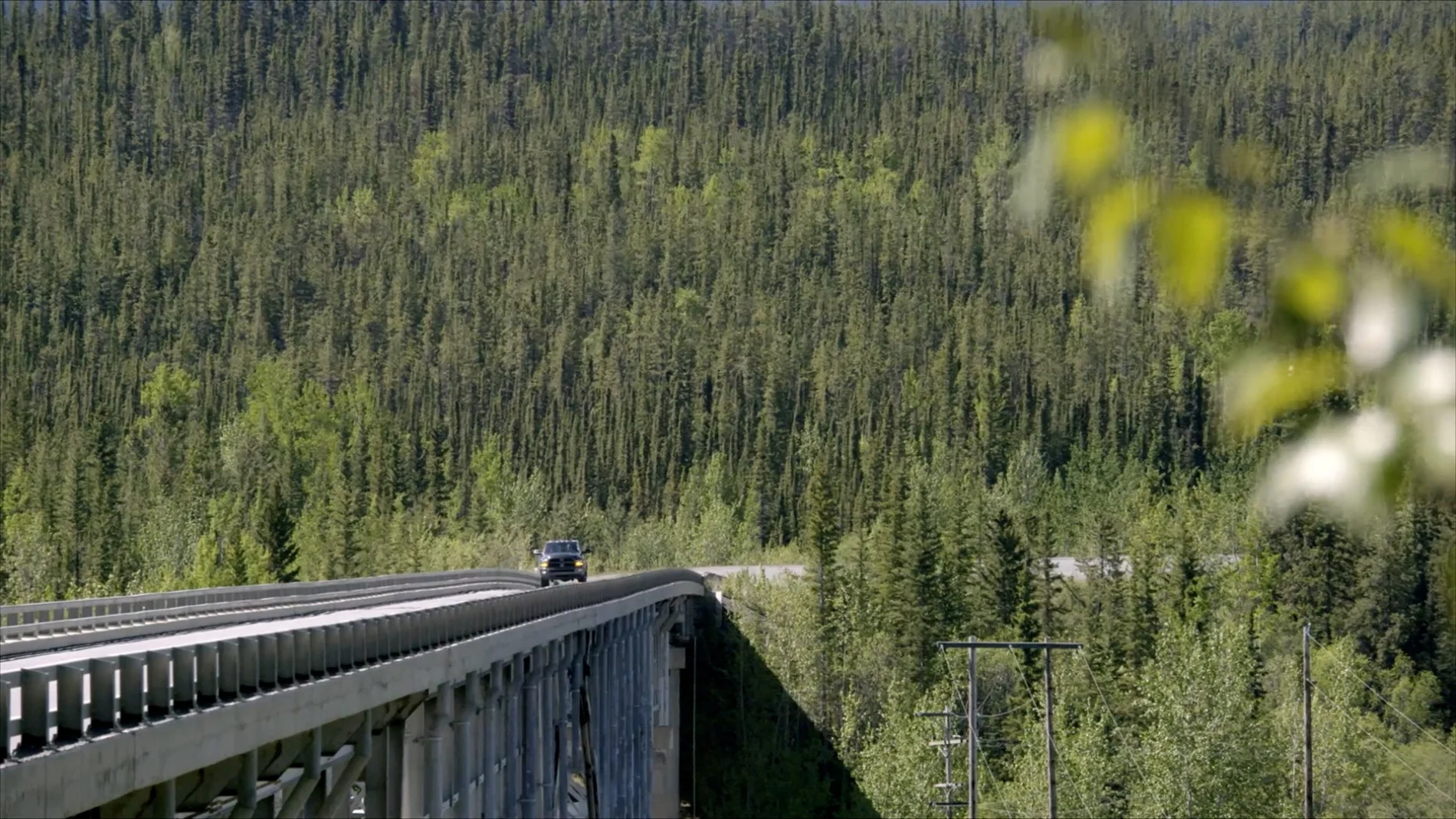Laboucan-Massimo and Hogan driving through a densely forested area in the Yukon. (Power to the People)