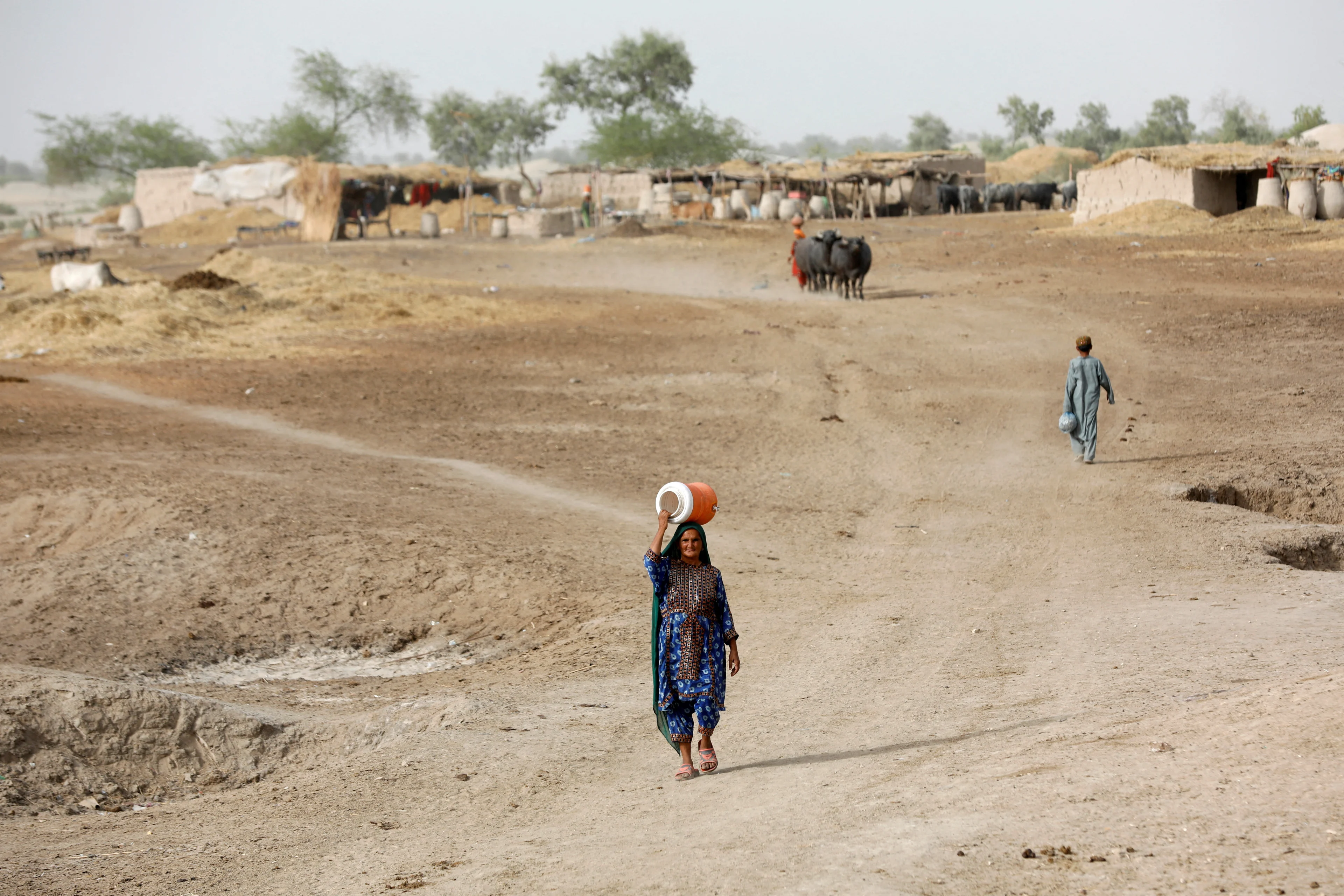 REUTERS: FOTO DO ILE: Uma mulher caminha para buscar água em uma bomba manual próxima com um bebedouro na cabeça, durante uma onda de calor, nos arredores de Jacobabad, Paquistão, 16 de maio de 2022. REUTERS/Akhtar Soomro/Foto de arquivo