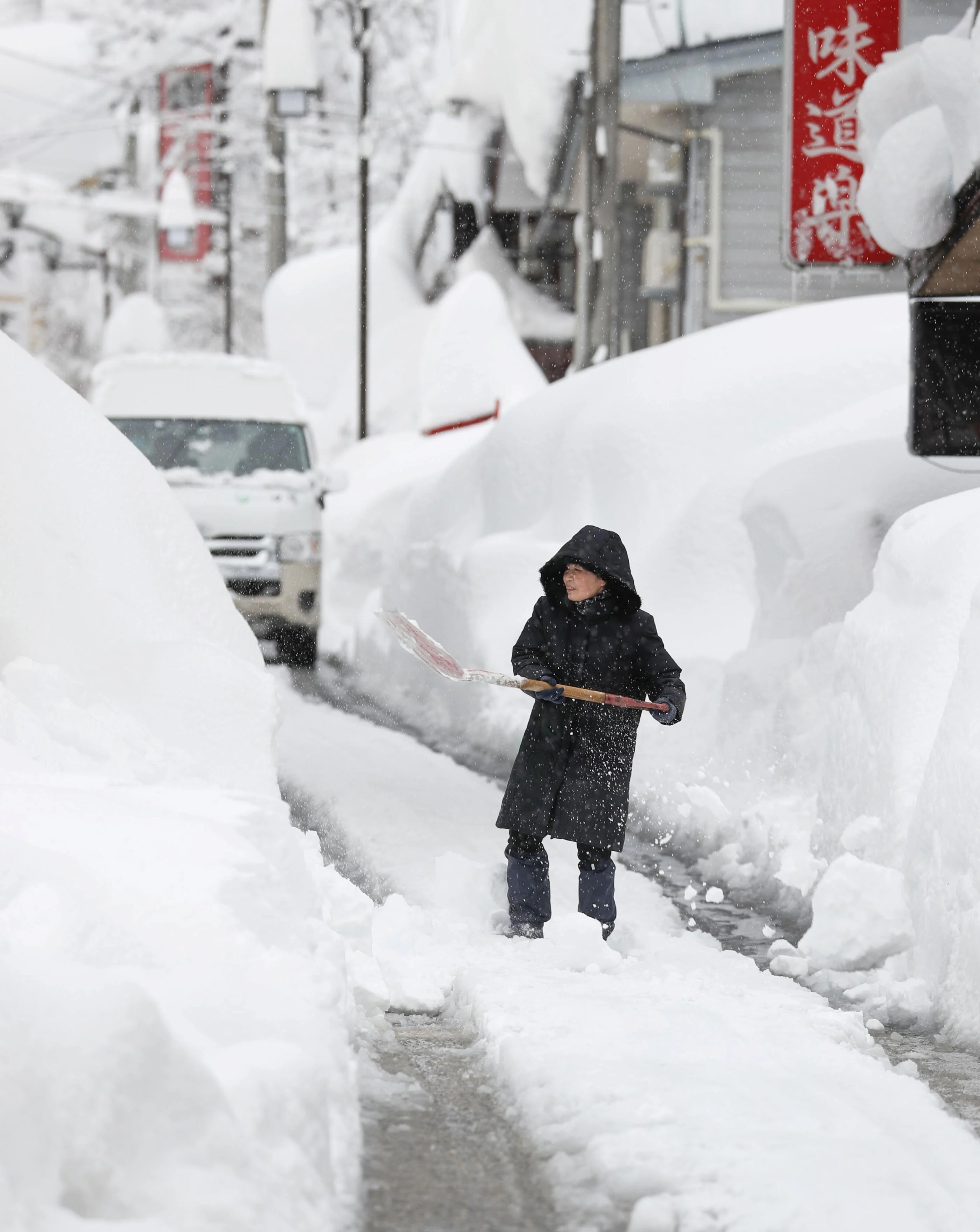 A woman removes snow on a street in Yuzawa, Niigata Prefecture, Japan in this photo taken by Kyodo December 17, 2020. Mandatory credit Kyodo/via REUTERS