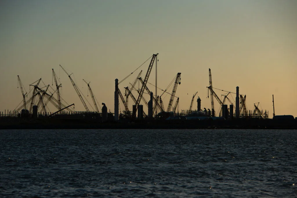 Construction cranes stand silhouetted by the sunset at the Golden Pass LNG Terminal in Sabine Pass, TX, on Thursday, April 14, 2022. Golden Pass LNG, a joint venture between ExxonMobil and Qatar Petroleum, began as an import terminal and construction seen today will create export capability. (The Washington Post/ Getty Images)