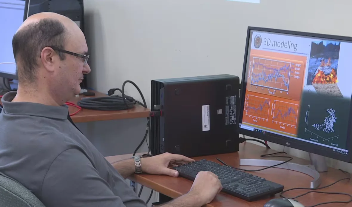 CBC: Moulay Akhloufi looks over computer modelling that predicts the spread of a wildfire based on environmental conditions. (Alexandre Silberman/CBC)