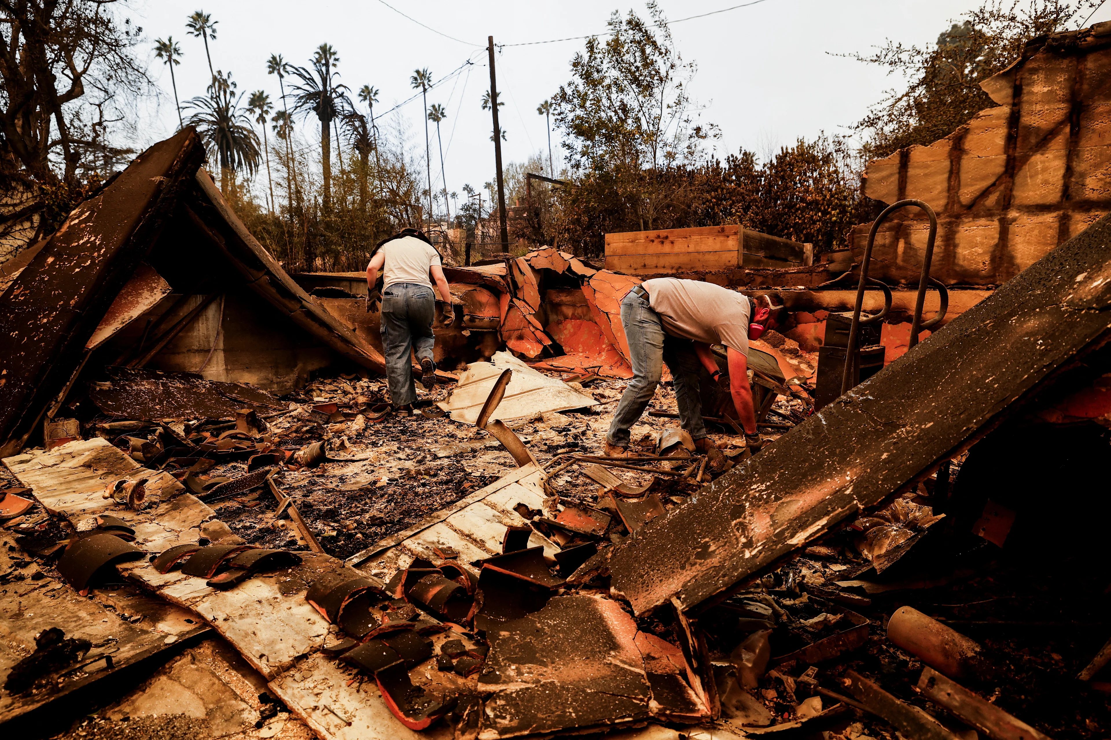 REUTERS: People search through the remains of a house that was burnt down by the Eaton Fire in Altadena, California, U.S. January 9, 2025. REUTERS/Fred Greaves