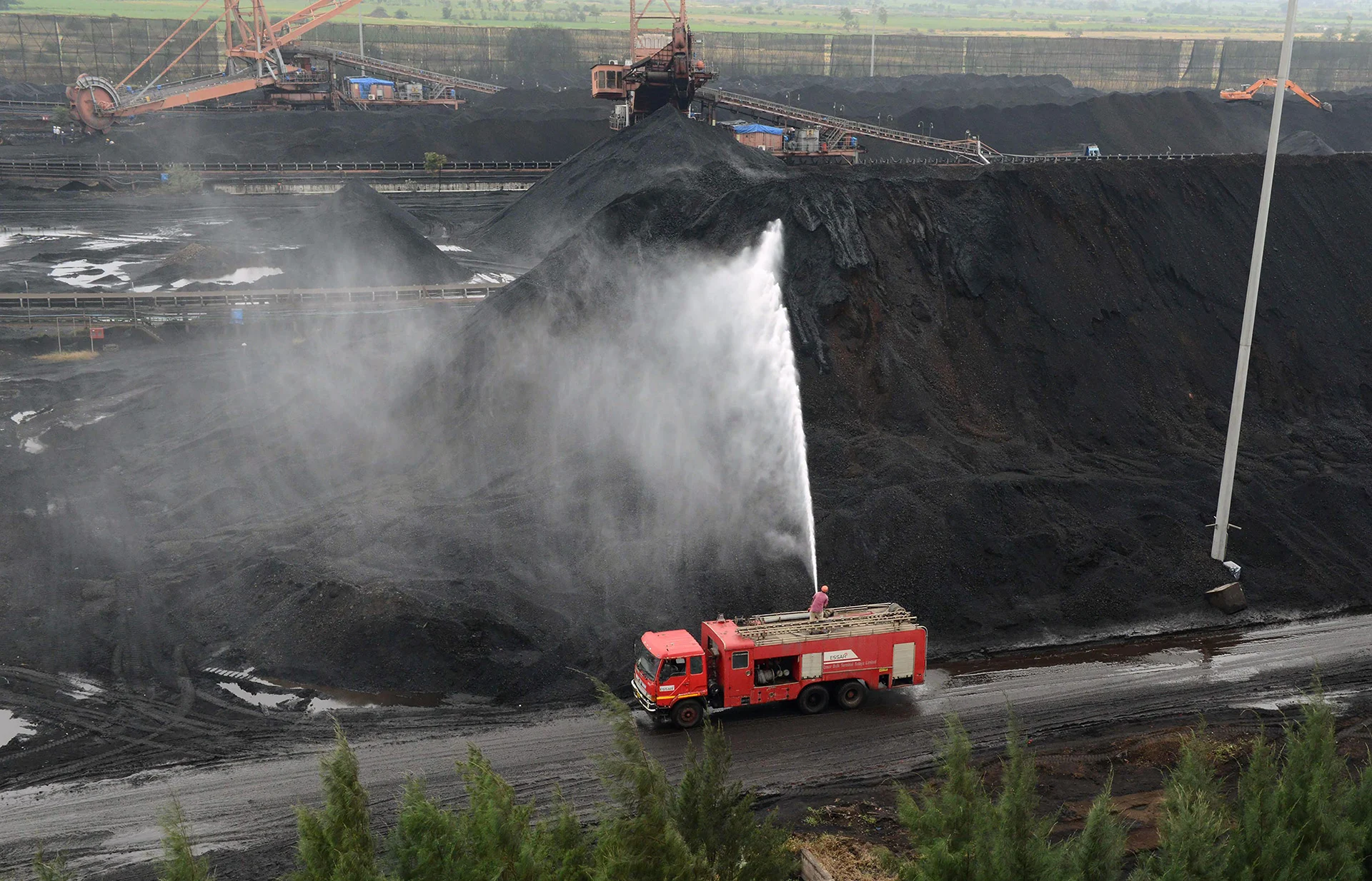 An Indian firefighter cools hot coal at a stockyard at a coal-fired thermal power plant belonging to Essar Power in Salaya, some 400 km from Ahmedabad, on Oct. 4, 2016. Essar Power Ltd. is one of India's largest private sector power producers and owns power plants in India and Canada. (Sam Panthaky / AFP / Getty Images)