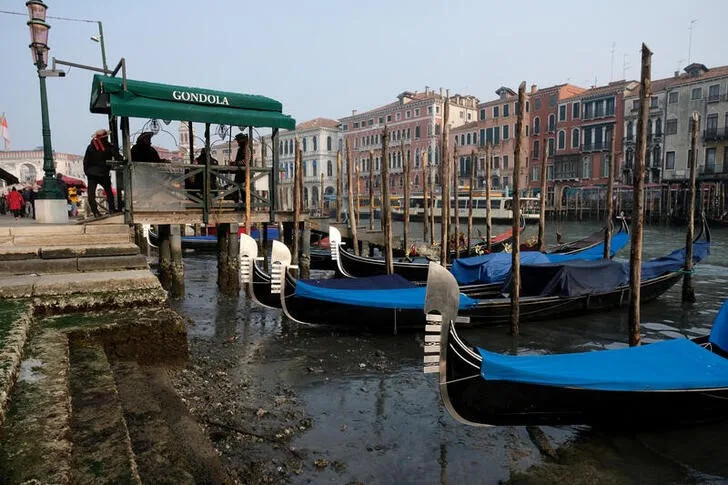REUTERS: Gondolas are pictured in the Grand Canal during a severe low tide in the lagoon city of Venice, Italy, February 17, 2023. REUTERS/Manuel Silvestri REFILE - CORRECTING YEAR
