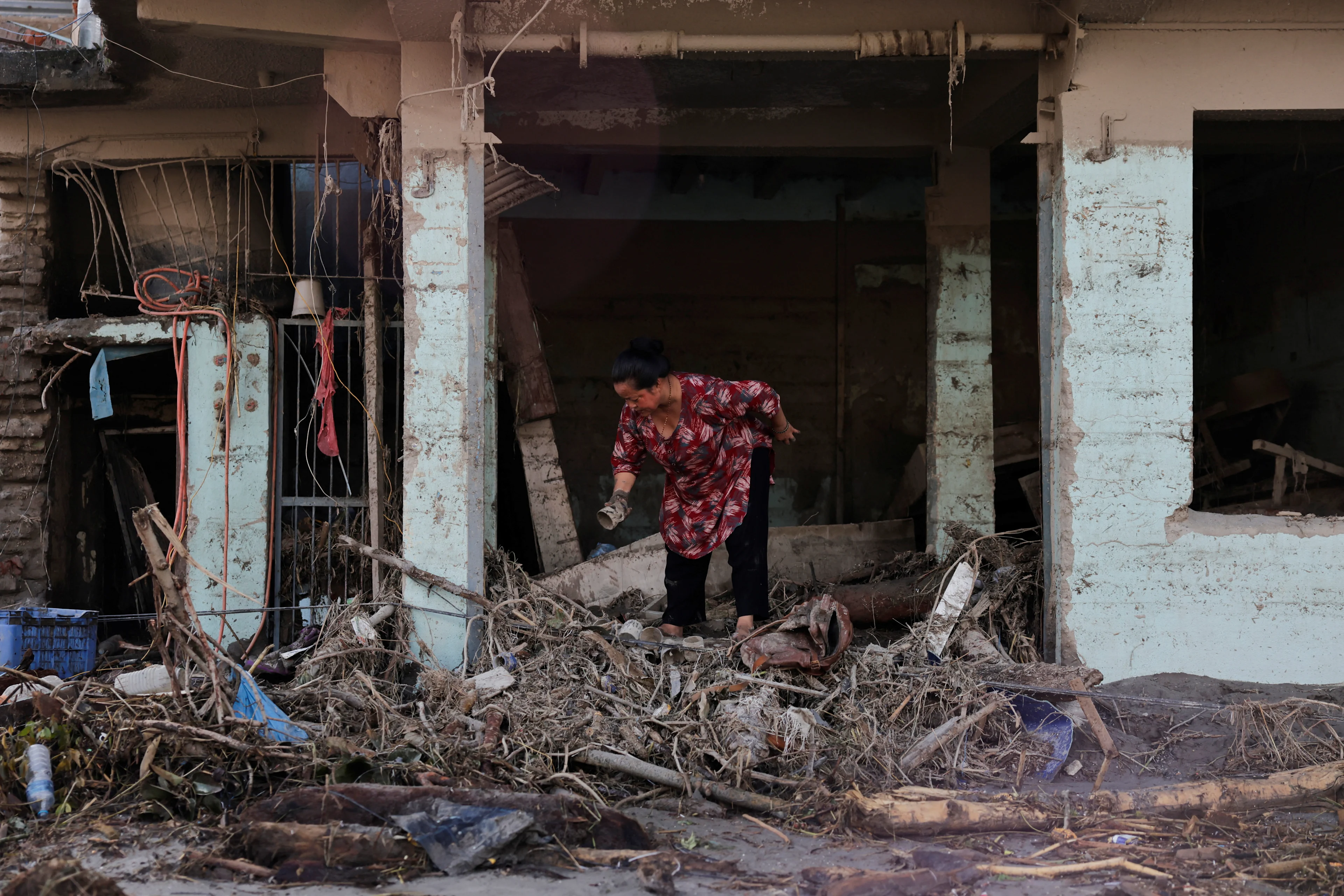 REUTERS: A woman searches for her belongings at a damaged shop following flash floods and a mudslide in Trishuli, Nuwakot district, Nepal, August 28, 2026. REUTERS/Navesh Chitrakar
