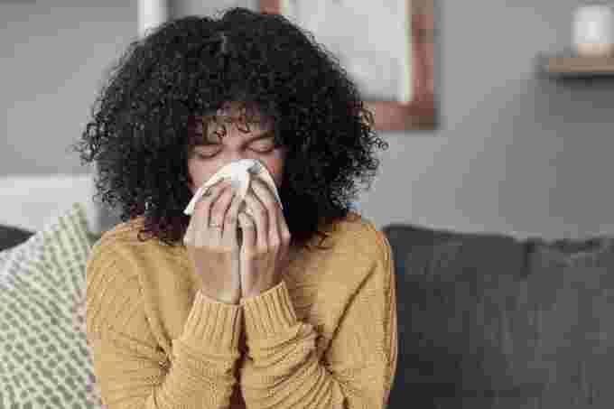 Getty Images: Woman sneezing into tissue during allergy season