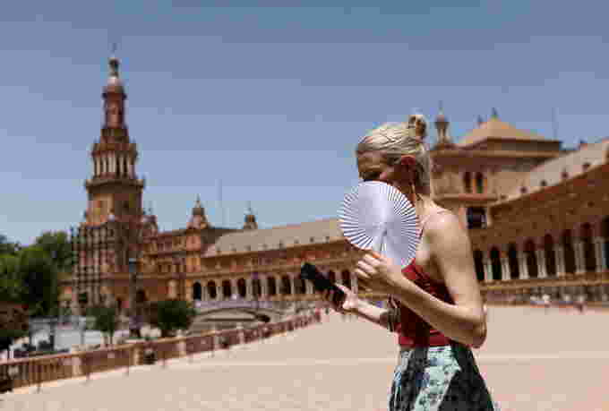 Spain heat /REUTERS - FILE PHOTO: A woman fans herself during the first heatwave of the year in Seville, Spain June 11, 2022. REUTERS/Marcelo del Pozo