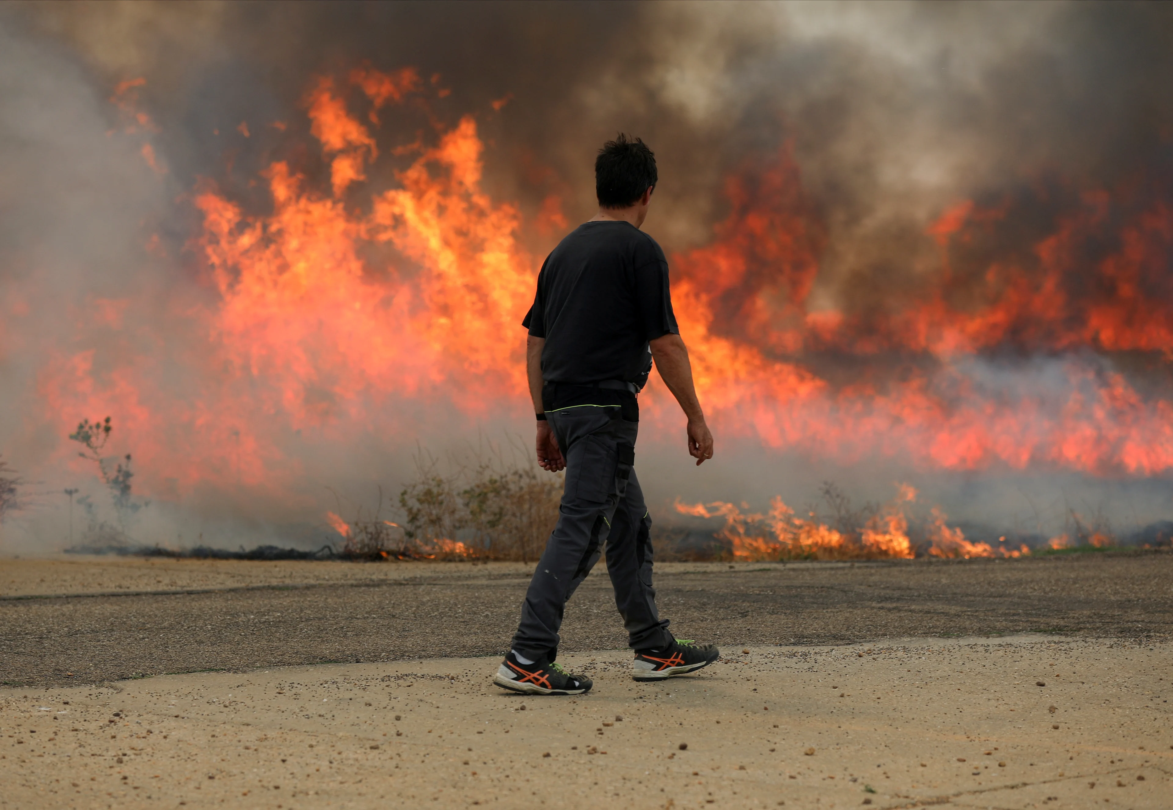 Reuters: A neighbour watches a fire burning a wheat field between Tabara and Losacio, during the second heatwave of the year, in the province of Zamora, Spain, July 18, 2022. REUTERS/Isabel Infantes