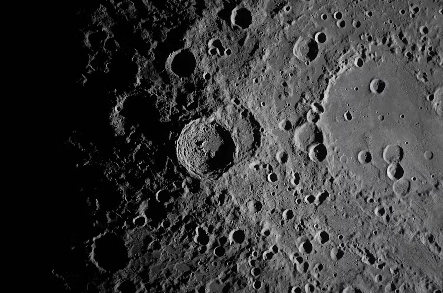 NASA: A close-up view taken by the Artemis II crew of Vavilov Crater on the rim of the older and larger Hertzsprung basin. The right portion of the image shows the transition from smooth material within an inner ring of mountains to more rugged terrain around the rim. The image was captured with a handheld camera at a focal length of 400 millimetres, around the far side of the moon. (NASA)