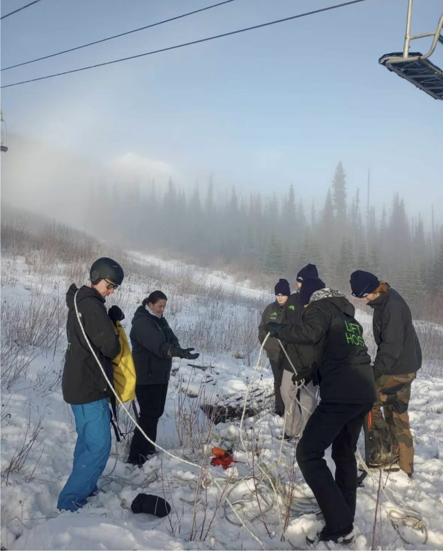 CBC: Staff members at Hudson Bay Mountain in Smithers, B.C., gather underneath a chairlift during training on Nov. 25, 2023. The ski hill is waiting for enough snow for it to open for the season. (Lex Rei-Jones/Submitted)