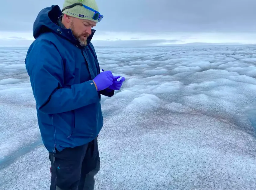 Professor Jason Box taking ice samples standing on exposed ice below the snow line of the Greenland Ice Sheet in West Greenland during the melt season (The Geological Survey of Denmark and Greenland, GEUS)
