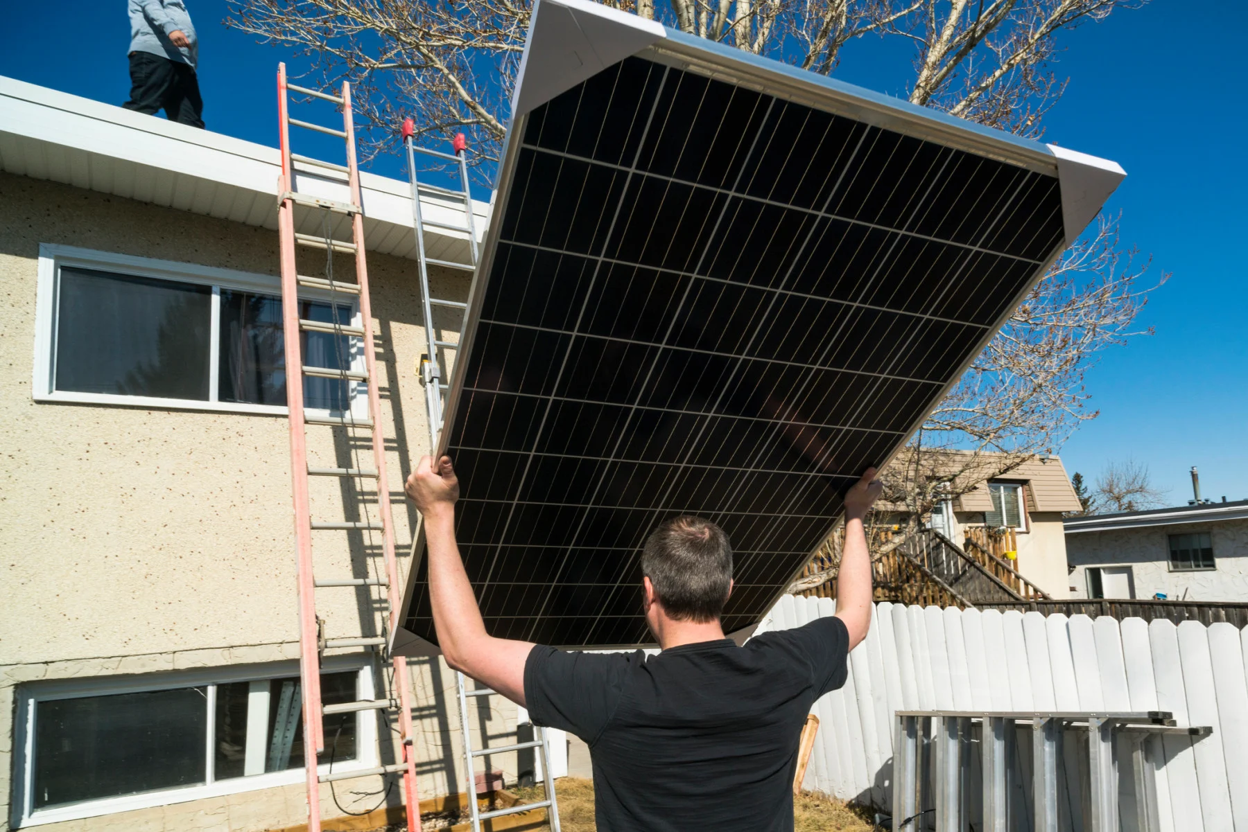 Workers moving solar modules while installing solar panels on a residential roof. (powerofforever/ E+/ Getty Images)