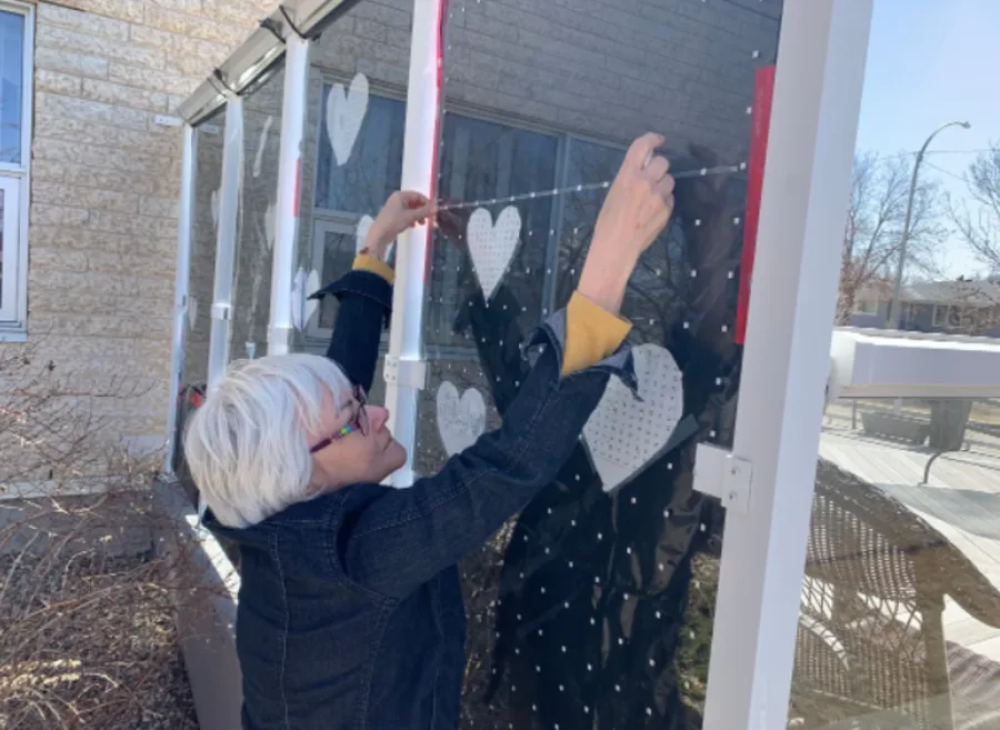 CBC: Elaine Ehman with the Bird Friendly City Team places feather-friendly tape on glass partition. (Fiona Odlum, CBC News)