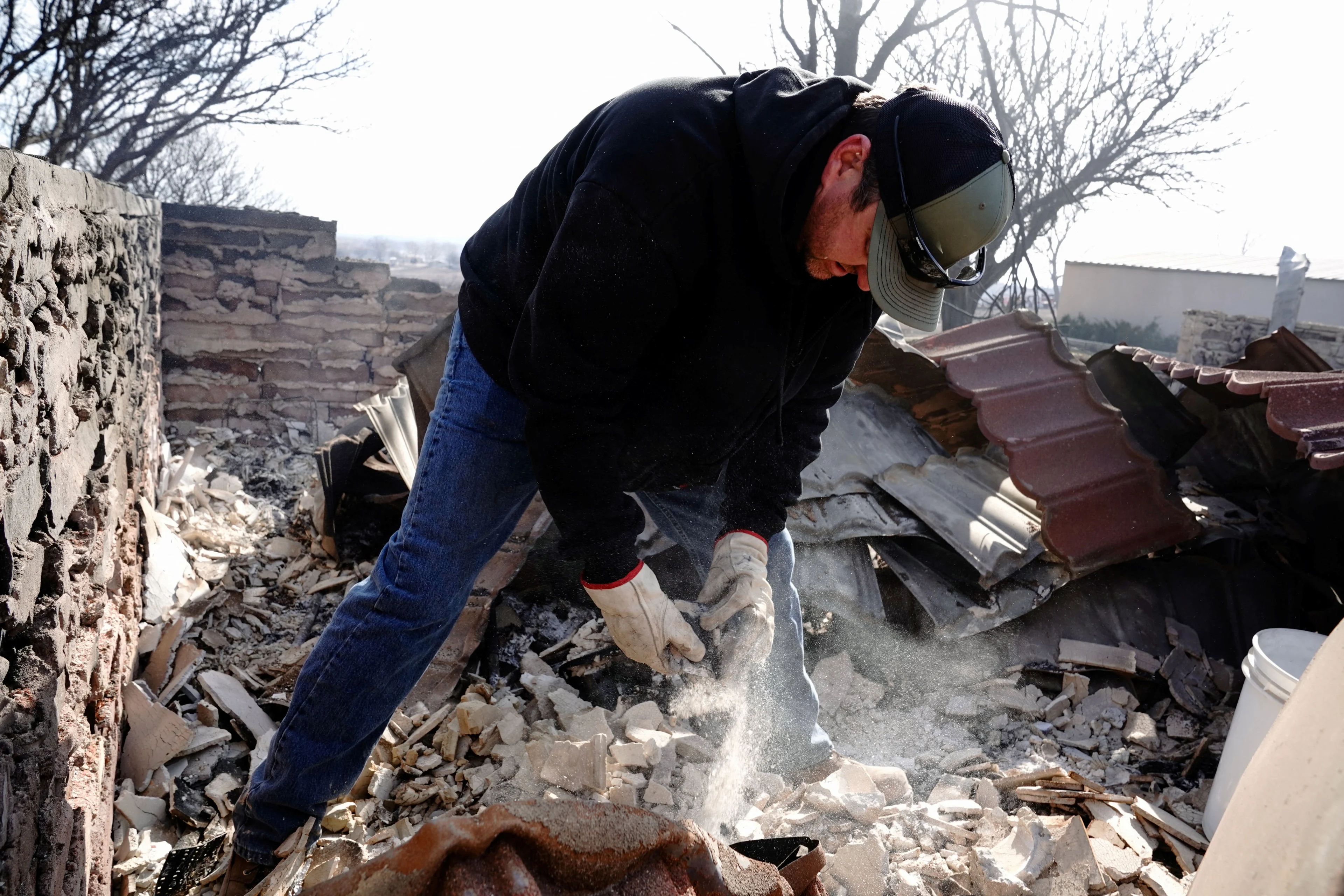 Reuters: Mason Holloway sifts through the remains of his aunts home that was destroyed by the Smokehouse Creek wildfire, in Canadian, Texas, U.S., February 28, 2024. REUTERS/Nick Oxford