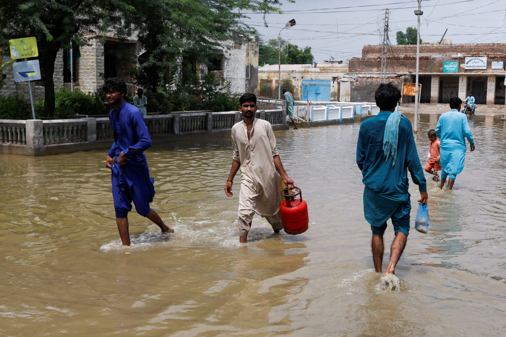 Men walk through rain waters, following rains and floods during the monsoon season in Jacobabad, Pakistan August 30, 2022. (REUTERS/Akhtar Soomro)