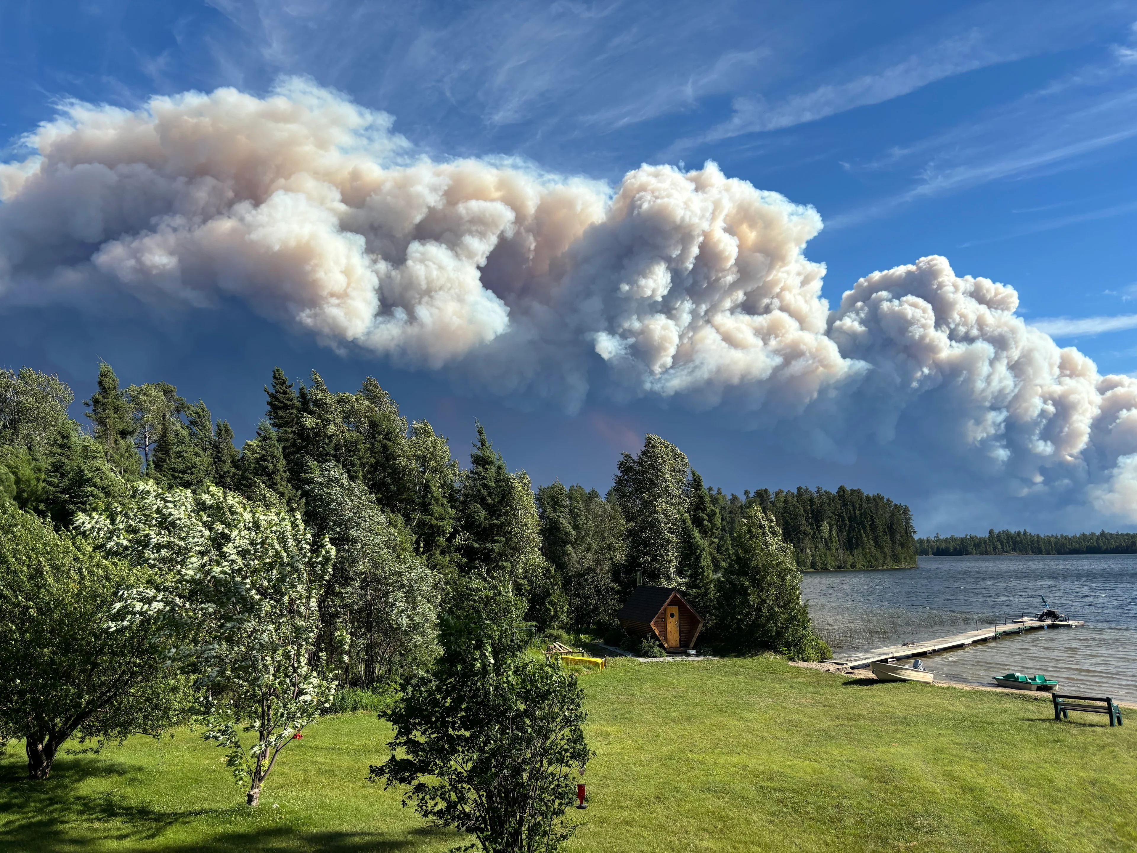 UGC: Wildfire smoke seen pluming over the trees from a camp in Quetico, Ont., on July 13, 2026 (Karen Boyd/UGC)