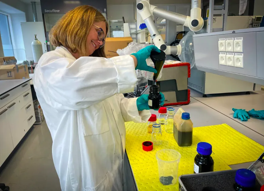 Julia Svensson, senior research engineer at MAN Energy Solutions, pours heavy bunker C fuel into a vial at the company's Copenhagen lab. (Lily Martin/CBC)