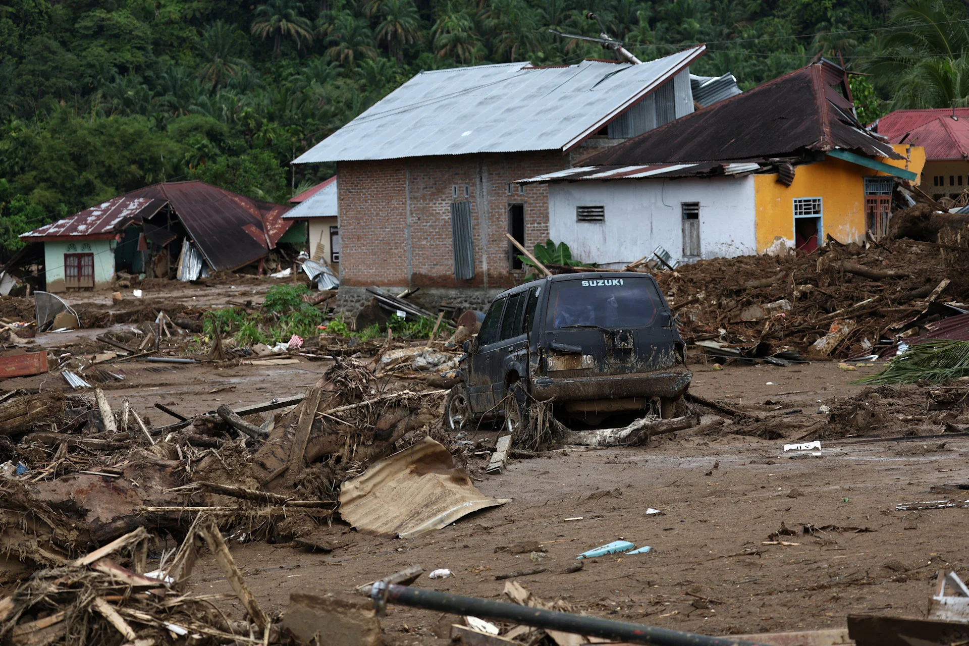 Reuters: A car stuck in the mud sits among debris at an area hit by deadly flash floods following heavy rains in Palembayan, Agam regency, West Sumatra province, Indonesia, December 2, 2025. REUTERS/Willy Kurniawan